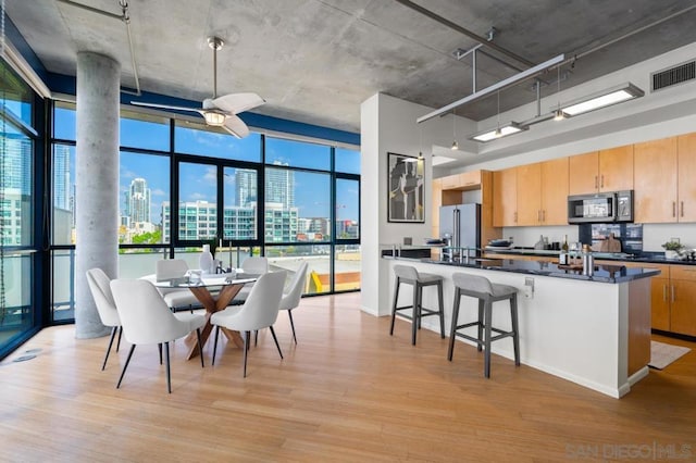 kitchen featuring ceiling fan, a wealth of natural light, high quality fridge, expansive windows, and light wood-type flooring