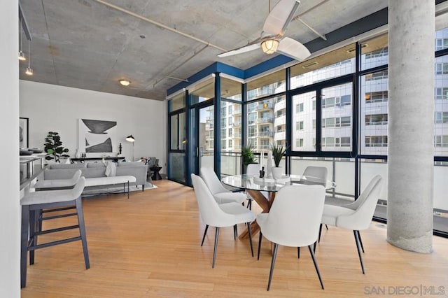 dining room with ceiling fan, hardwood / wood-style flooring, and a wall of windows