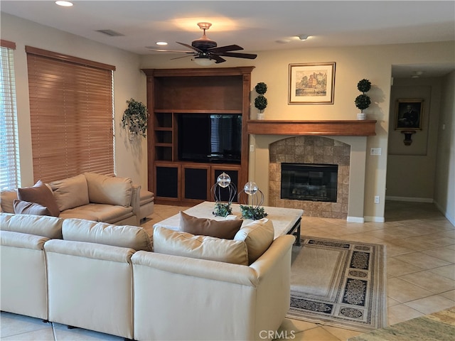 tiled living room with a tiled fireplace and ceiling fan