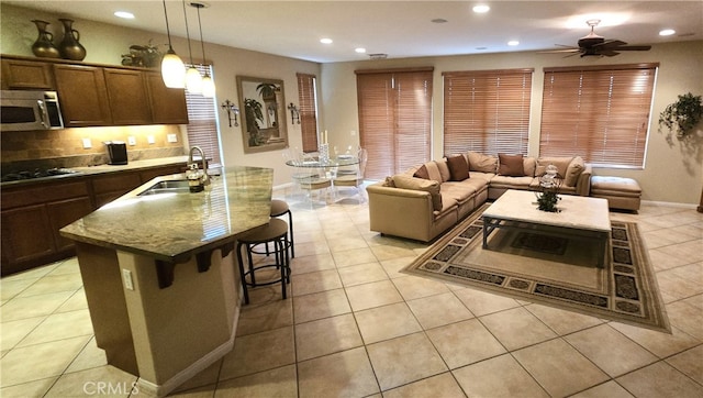 kitchen with gas stovetop, a kitchen island with sink, a breakfast bar area, sink, and decorative light fixtures