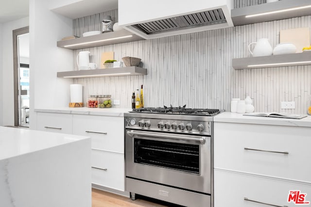 kitchen featuring white cabinets, high end range, light hardwood / wood-style flooring, ventilation hood, and light stone countertops