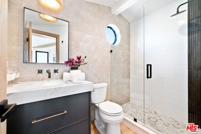 bathroom with tile walls, vaulted ceiling with beams, a shower with shower door, vanity, and toilet