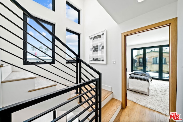 stairway featuring a wealth of natural light and hardwood / wood-style flooring