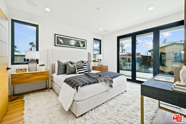 bedroom featuring light wood-type flooring, multiple windows, and access to exterior