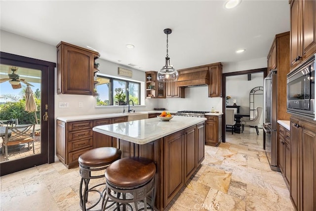 kitchen featuring custom exhaust hood, decorative light fixtures, a kitchen island, a kitchen bar, and stainless steel appliances