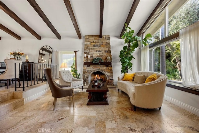 living area with beam ceiling and a stone fireplace