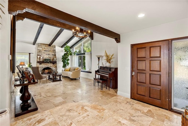 foyer featuring a notable chandelier, vaulted ceiling with beams, and a fireplace