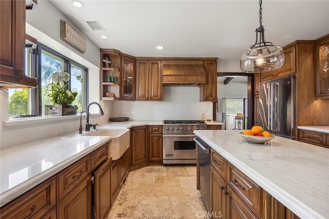 kitchen featuring light stone countertops, custom exhaust hood, sink, pendant lighting, and high quality appliances