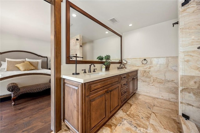 bathroom with wood-type flooring, vanity, and tile walls