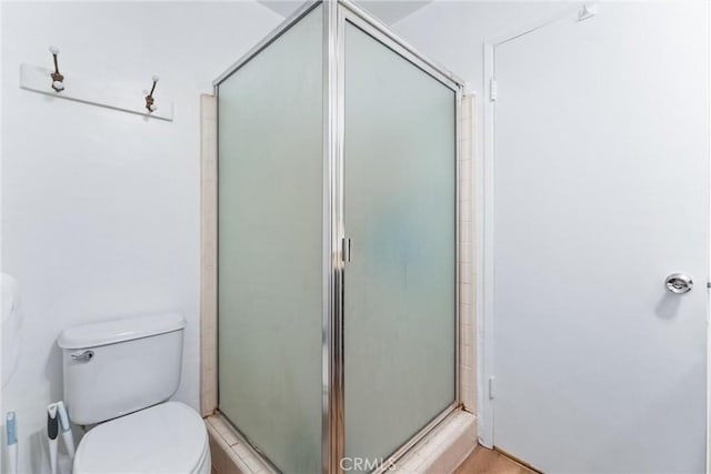 bathroom with a shower with shower door and toilet