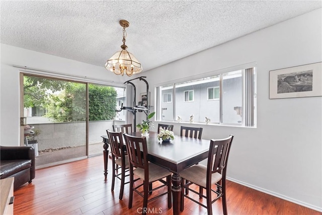 dining area featuring hardwood / wood-style floors, a textured ceiling, and an inviting chandelier