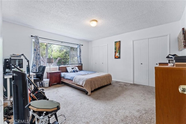 carpeted bedroom featuring a textured ceiling and multiple closets