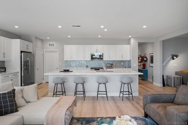 kitchen with white cabinets, an island with sink, appliances with stainless steel finishes, and a kitchen breakfast bar