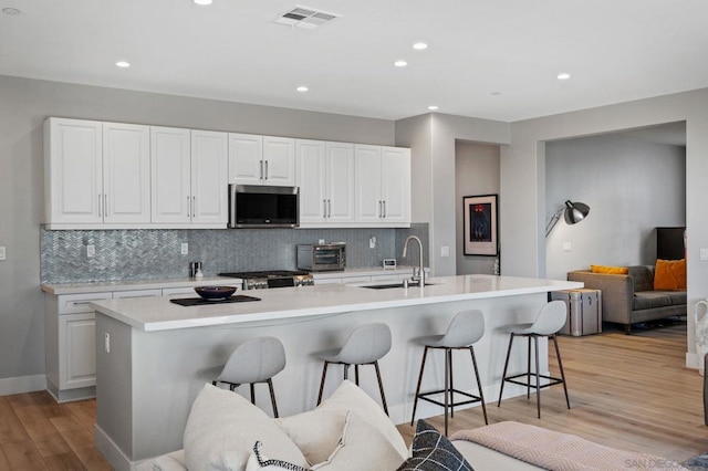 kitchen featuring a center island with sink, appliances with stainless steel finishes, sink, and white cabinetry