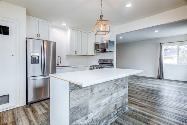 kitchen featuring appliances with stainless steel finishes, hanging light fixtures, white cabinets, dark hardwood / wood-style flooring, and sink