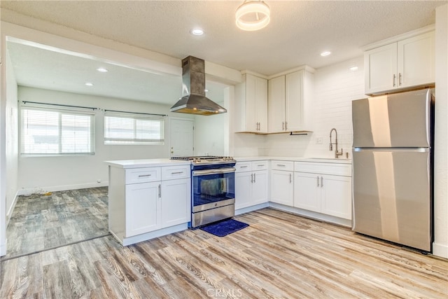 kitchen featuring sink, white cabinetry, kitchen peninsula, wall chimney exhaust hood, and stainless steel appliances