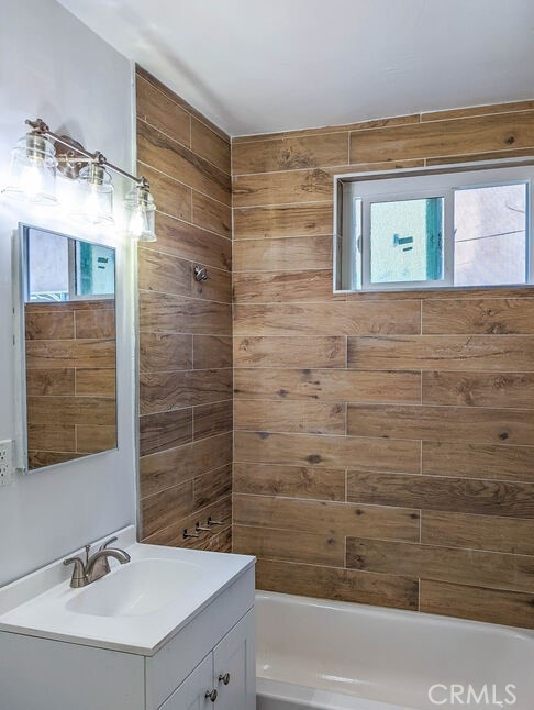 bathroom with tiled shower / bath combo and vanity