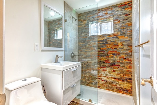 bathroom with a tile shower, vanity, and toilet