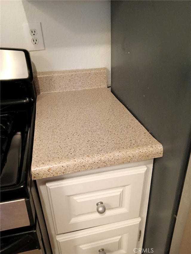 details featuring white cabinets and light stone counters