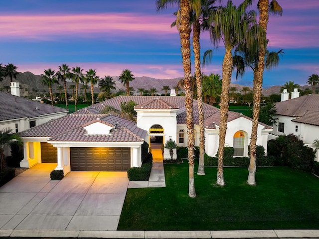 mediterranean / spanish house with a mountain view, a garage, and a yard