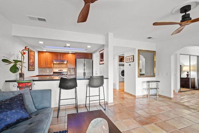 living room with washer / dryer, ceiling fan, and light tile patterned floors