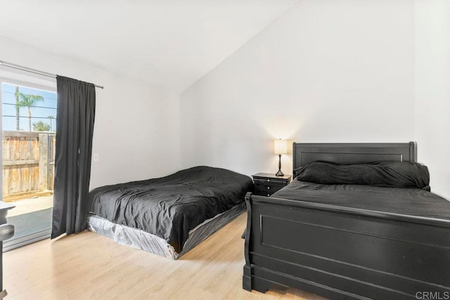 bedroom featuring access to outside, lofted ceiling, and wood-type flooring