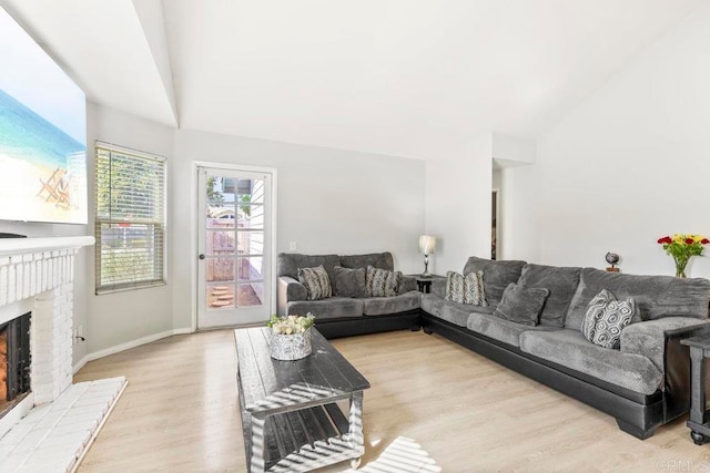 living room featuring a brick fireplace, light wood-type flooring, and lofted ceiling