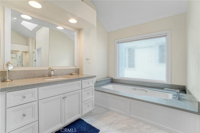 bathroom featuring lofted ceiling with skylight, vanity, and a bath