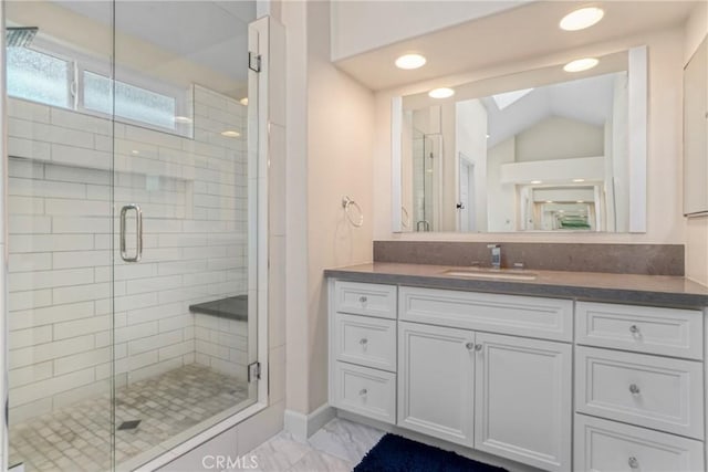 bathroom featuring vaulted ceiling with skylight, vanity, and an enclosed shower