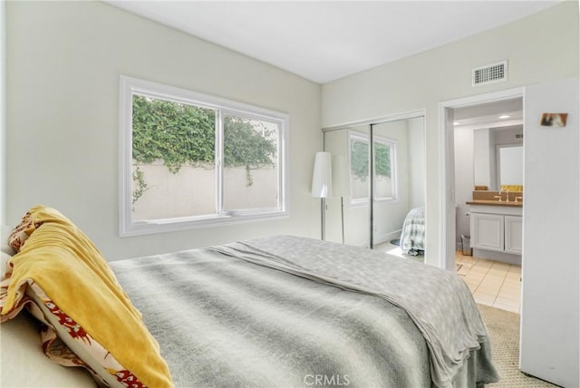 tiled bedroom featuring connected bathroom and a closet