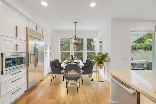 dining space featuring light hardwood / wood-style floors, a wealth of natural light, and a chandelier