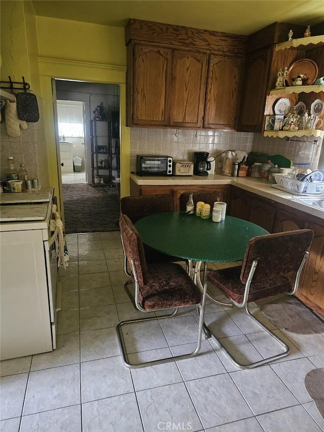 kitchen featuring white range oven, backsplash, and light tile patterned floors