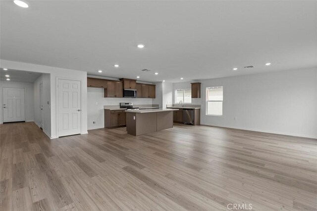 kitchen with light wood-type flooring, appliances with stainless steel finishes, sink, and a kitchen island