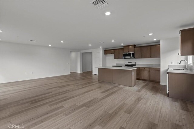 kitchen featuring light wood-type flooring, appliances with stainless steel finishes, a center island, and sink