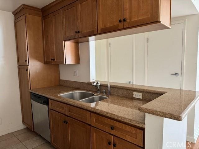 kitchen featuring dishwasher, sink, light stone counters, kitchen peninsula, and light tile patterned floors