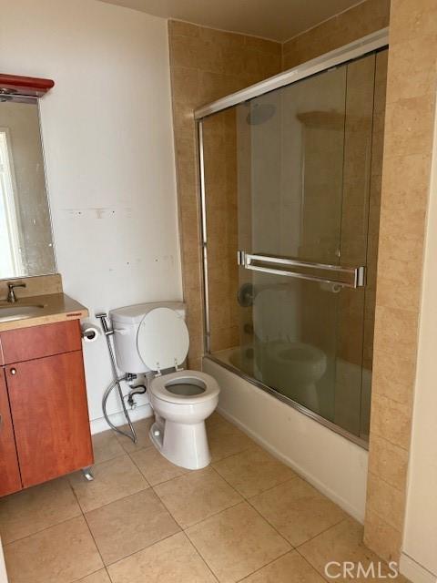 full bathroom featuring combined bath / shower with glass door, vanity, tile patterned floors, and toilet