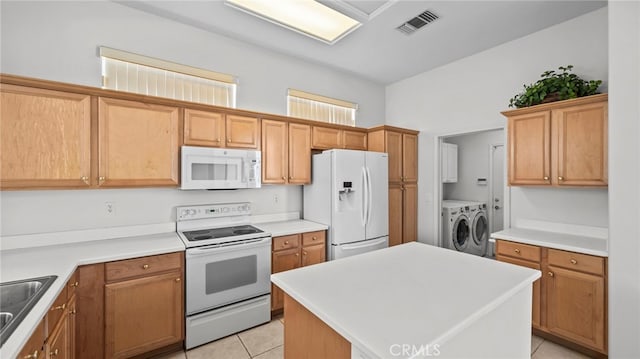 kitchen with washing machine and dryer, white appliances, sink, a center island, and light tile patterned flooring