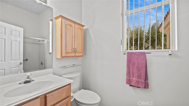 bathroom with a shower with door, vanity, and toilet