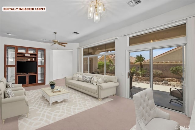 carpeted living room featuring ceiling fan with notable chandelier