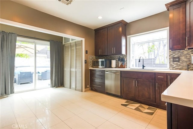 kitchen featuring dishwasher, light tile patterned floors, backsplash, and sink