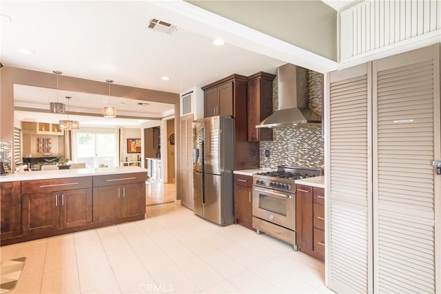 kitchen featuring decorative backsplash, wall chimney range hood, stainless steel appliances, and decorative light fixtures