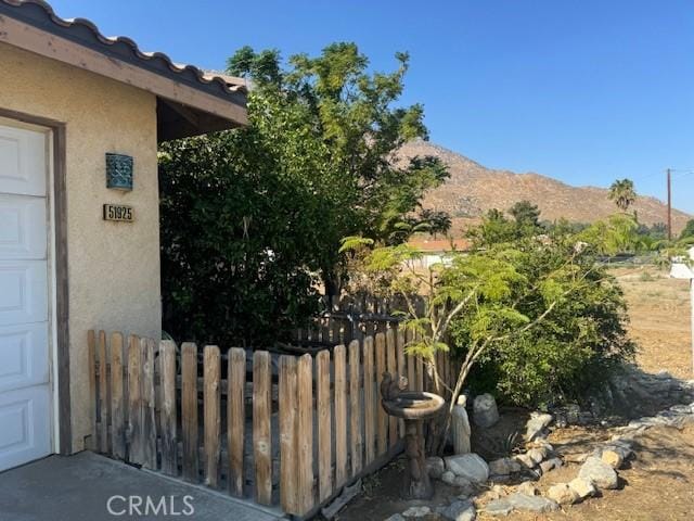 exterior space featuring a garage, fence, a mountain view, and stucco siding