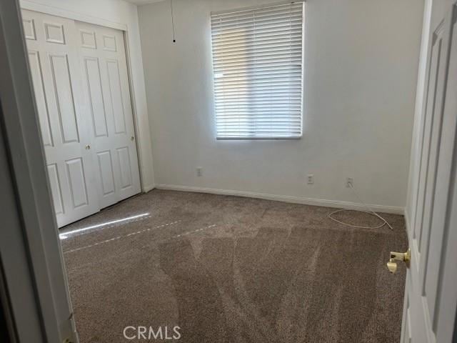 unfurnished bedroom featuring carpet floors, a closet, and baseboards