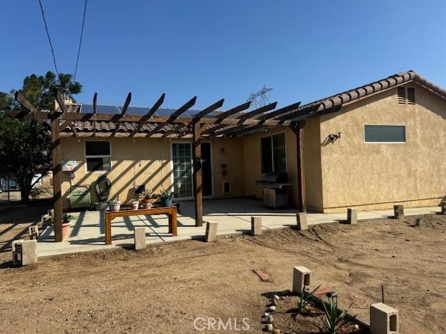 back of house featuring solar panels, a patio area, and stucco siding