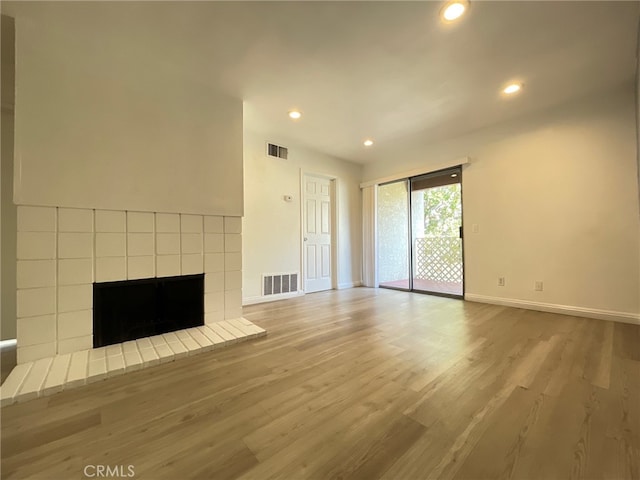 unfurnished living room with light hardwood / wood-style flooring and a tile fireplace