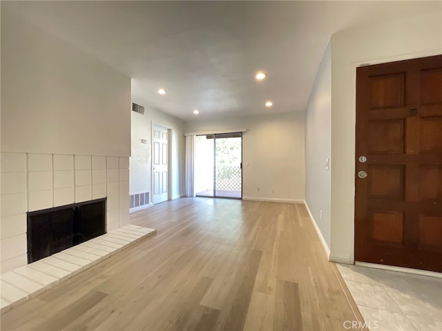 unfurnished living room featuring light wood-type flooring and a tile fireplace