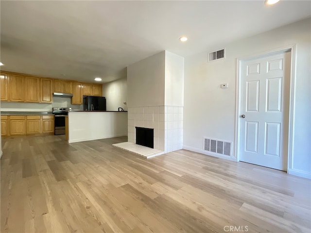 unfurnished living room with light hardwood / wood-style flooring and a tile fireplace