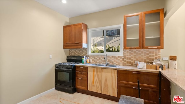 kitchen with tasteful backsplash, sink, black range with gas stovetop, light tile patterned floors, and light stone countertops