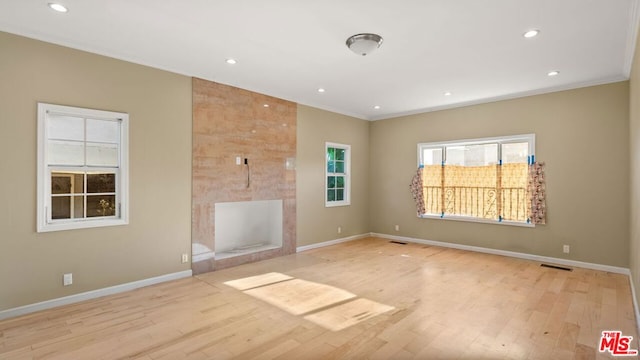 unfurnished living room featuring ornamental molding, light hardwood / wood-style floors, and a fireplace