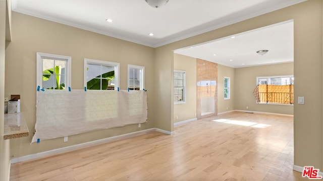 spare room with ornamental molding, light wood-type flooring, and a healthy amount of sunlight